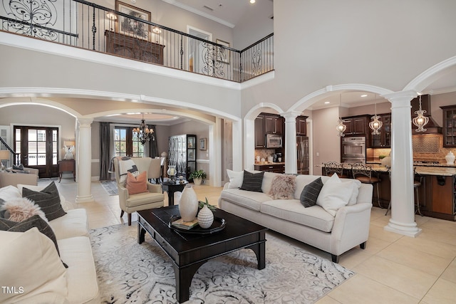 living room with arched walkways, crown molding, light tile patterned floors, a chandelier, and ornate columns