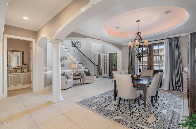 dining room with a tray ceiling, decorative columns, arched walkways, stairs, and a notable chandelier