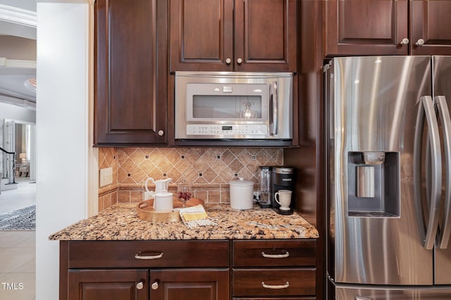 kitchen featuring stainless steel appliances, backsplash, and dark brown cabinets