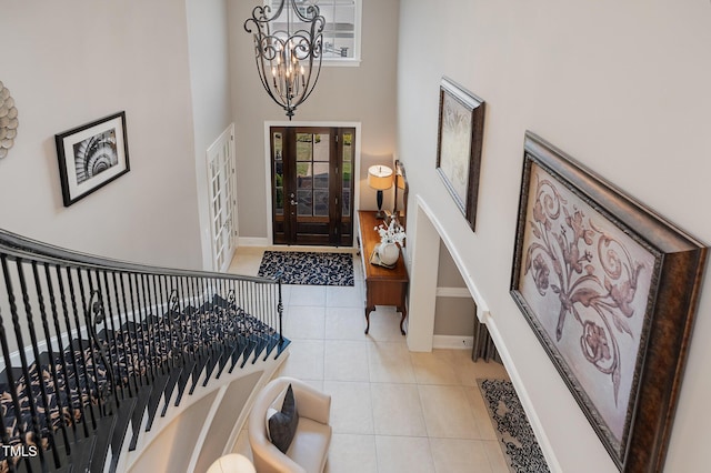 entryway featuring baseboards, a chandelier, french doors, a high ceiling, and light tile patterned flooring