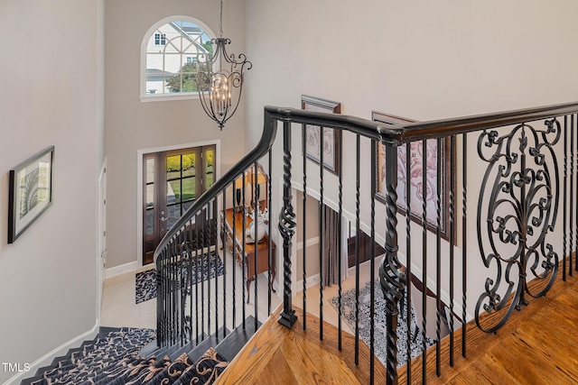 stairs with baseboards, a chandelier, and a towering ceiling