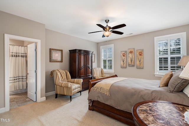 bedroom with visible vents, ensuite bathroom, baseboards, light colored carpet, and ceiling fan