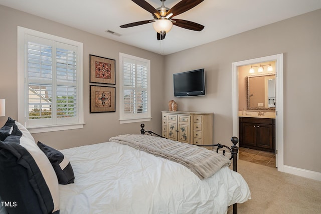 bedroom featuring baseboards, visible vents, a sink, ensuite bathroom, and light carpet