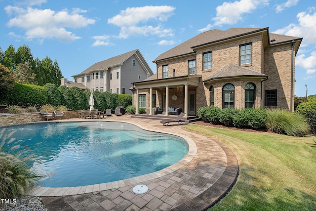 outdoor pool with a yard and a patio area