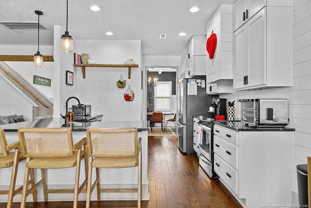 kitchen with white cabinetry, appliances with stainless steel finishes, dark hardwood / wood-style flooring, and a breakfast bar area