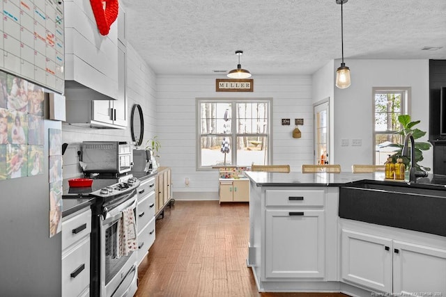 kitchen with sink, white cabinetry, stainless steel electric range oven, hanging light fixtures, and dark hardwood / wood-style floors