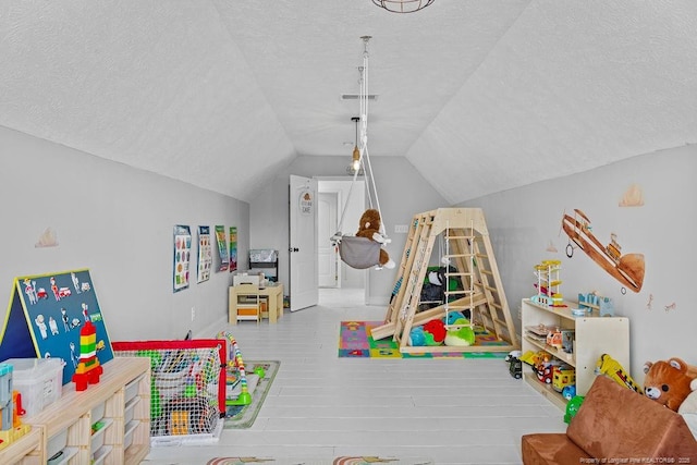 game room featuring lofted ceiling, wood-type flooring, and a textured ceiling