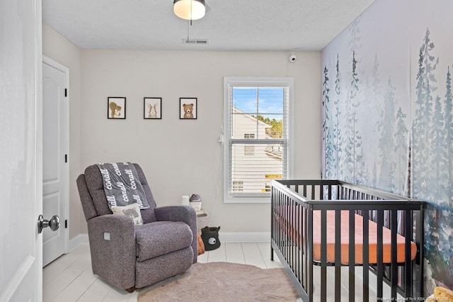 bedroom featuring light tile patterned floors, a crib, and a textured ceiling