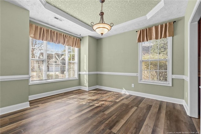 unfurnished dining area with wood-type flooring, a raised ceiling, and a textured ceiling