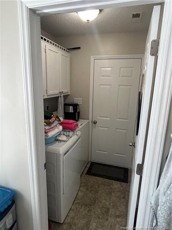 washroom with cabinets, a textured ceiling, and washer and clothes dryer