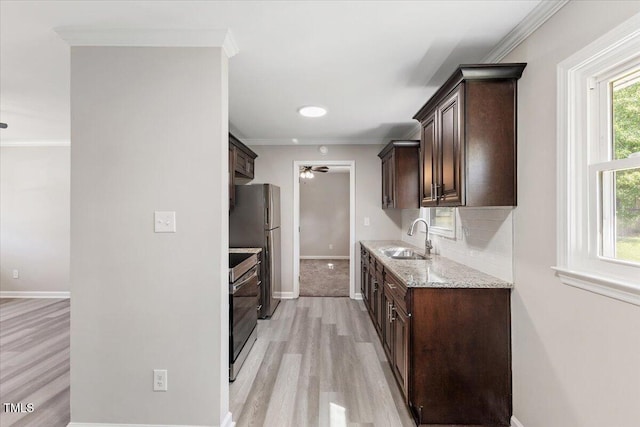 kitchen with dark brown cabinetry, sink, crown molding, range, and stainless steel fridge