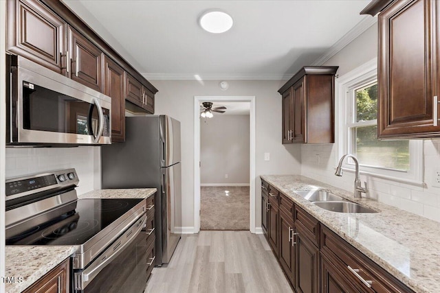 kitchen featuring crown molding, appliances with stainless steel finishes, sink, and light stone counters