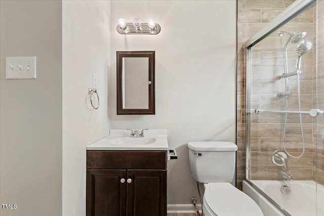 full bathroom featuring vanity, combined bath / shower with glass door, and toilet