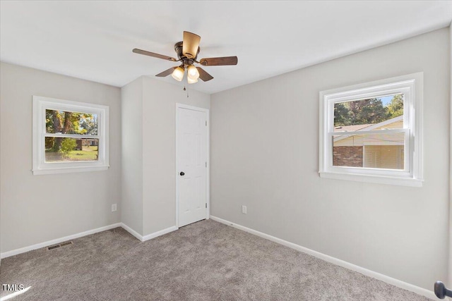 unfurnished bedroom with multiple windows, light colored carpet, and ceiling fan