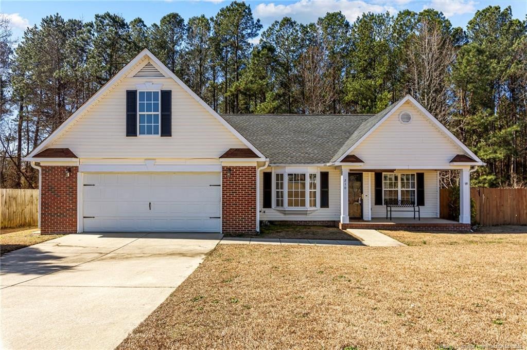 view of front of house with a garage, a front yard, and a porch