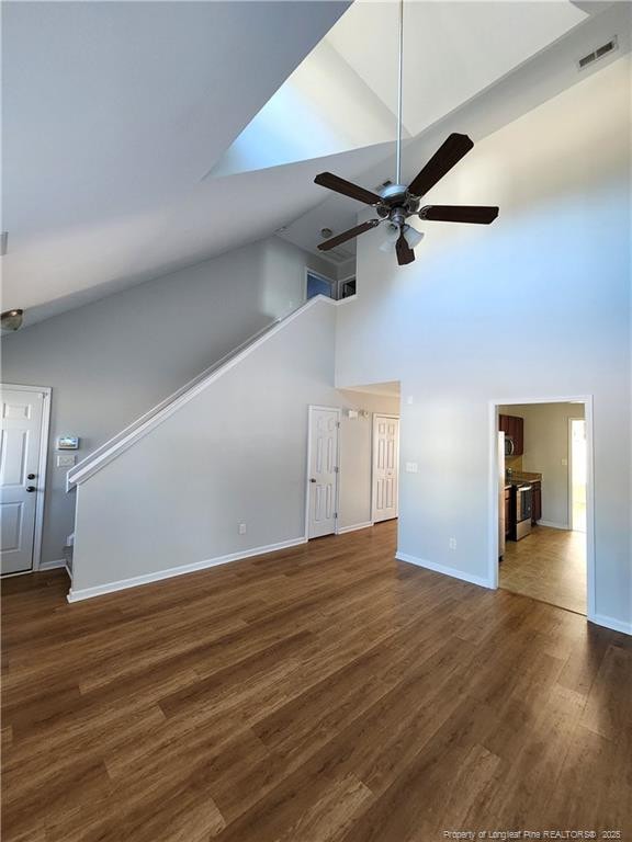 unfurnished living room featuring dark hardwood / wood-style flooring, high vaulted ceiling, and ceiling fan