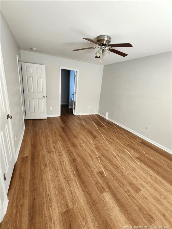 unfurnished bedroom with hardwood / wood-style flooring, a spacious closet, ceiling fan, and a closet