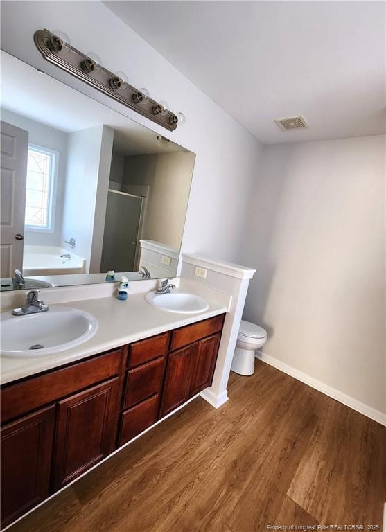 full bathroom featuring shower with separate bathtub, hardwood / wood-style floors, vanity, and toilet