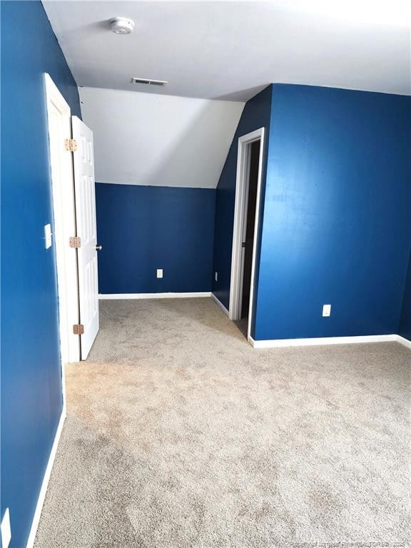 bonus room with light colored carpet and vaulted ceiling