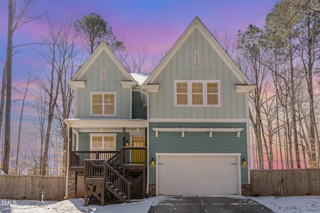 view of front of home featuring covered porch, driveway, board and batten siding, and fence