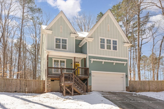 view of front of house featuring a porch, an attached garage, board and batten siding, fence, and driveway