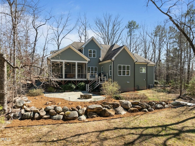 rear view of property featuring a sunroom, an outdoor fire pit, and a patio area