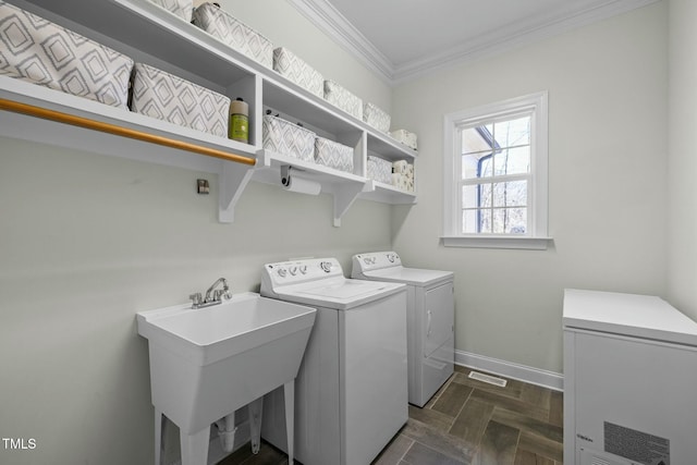 laundry area with laundry area, baseboards, ornamental molding, separate washer and dryer, and a sink