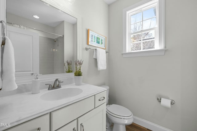 bathroom with curtained shower, toilet, vanity, wood finished floors, and baseboards