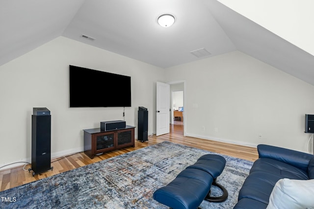 living room with lofted ceiling, baseboards, visible vents, and wood finished floors