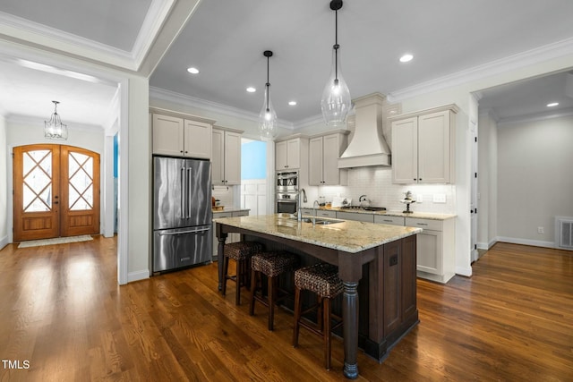 kitchen featuring visible vents, appliances with stainless steel finishes, custom exhaust hood, french doors, and a kitchen bar