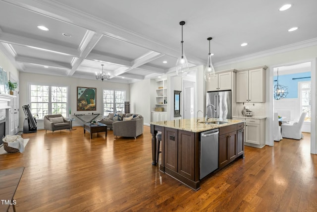 kitchen with stainless steel appliances, a glass covered fireplace, a sink, and an inviting chandelier