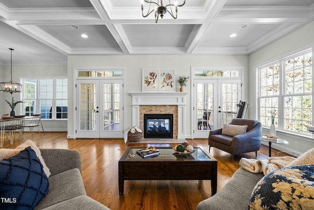 living room featuring french doors, coffered ceiling, wood finished floors, and an inviting chandelier