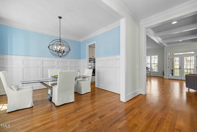 dining space featuring wood finished floors, french doors, beamed ceiling, an inviting chandelier, and crown molding