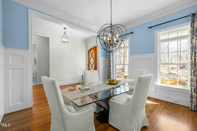 dining space featuring a chandelier, ornamental molding, wood finished floors, and a healthy amount of sunlight