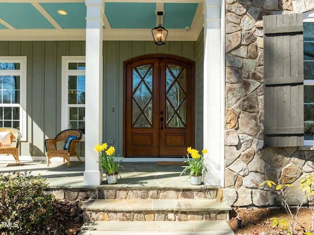 entrance to property featuring a porch, stone siding, and board and batten siding