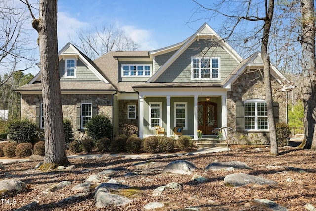 view of front of house featuring stone siding, a porch, and a shingled roof