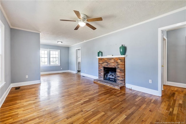 unfurnished living room featuring hardwood / wood-style floors, crown molding, a textured ceiling, and a brick fireplace