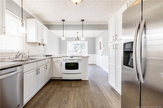 kitchen featuring sink, hanging light fixtures, appliances with stainless steel finishes, kitchen peninsula, and white cabinets