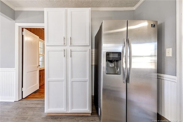 kitchen with white cabinets, crown molding, light hardwood / wood-style floors, stainless steel refrigerator with ice dispenser, and a textured ceiling