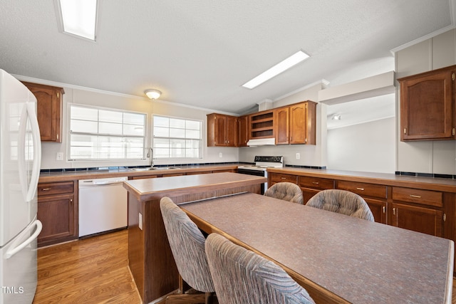 kitchen featuring sink, white appliances, light hardwood / wood-style floors, a textured ceiling, and vaulted ceiling