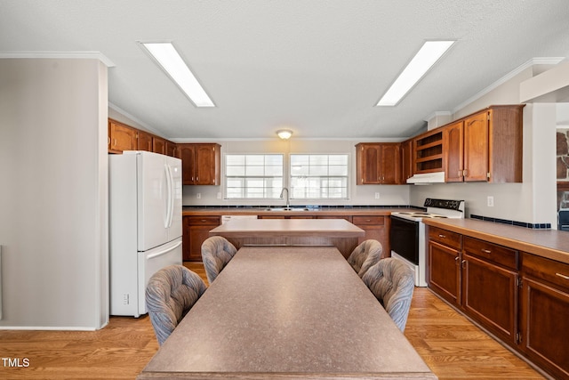 kitchen featuring crown molding, white appliances, lofted ceiling, and light wood-type flooring