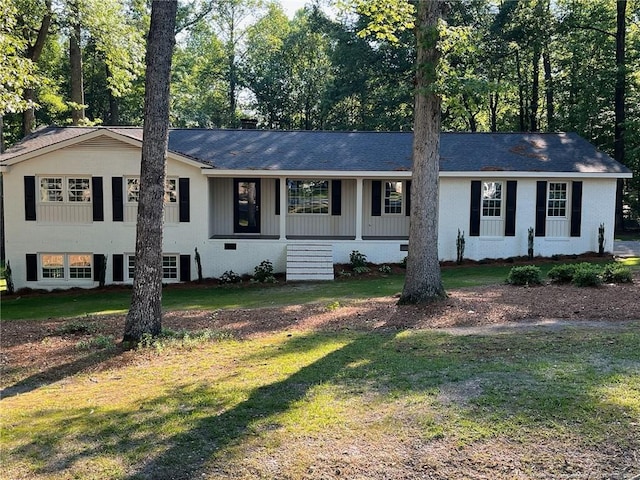 view of front of house featuring a front yard, covered porch, and view of scattered trees