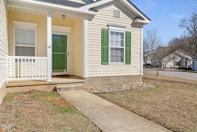 entrance to property featuring covered porch and a yard