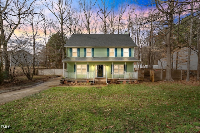 colonial house featuring a lawn and covered porch