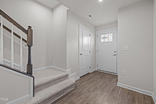 entryway with visible vents, wood finished floors, baseboards, and stairway