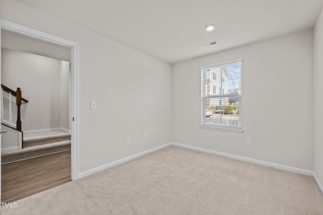 spare room with carpet, visible vents, baseboards, and stairway