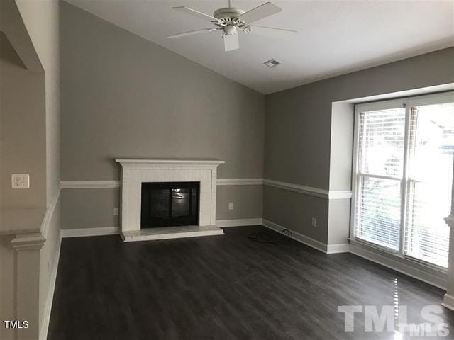 unfurnished living room with ceiling fan, a wealth of natural light, dark wood-type flooring, and vaulted ceiling