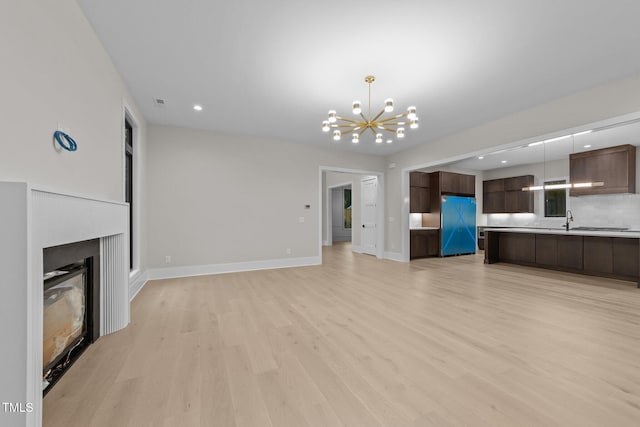 2305 Turners Aly, Raleigh, NC 27607 - unfurnished living room featuring a chandelier, light wood finished floors, recessed lighting, and a glass covered fireplace