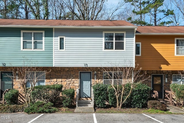 view of property featuring stone siding and uncovered parking