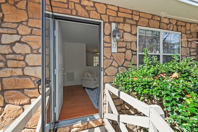 property entrance with stone siding and visible vents